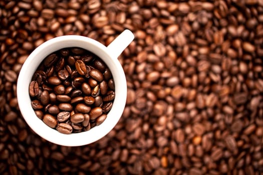 A White cup with coffee beans on a background of coffee beans