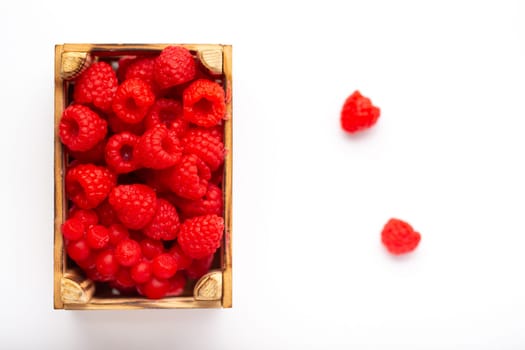 Some raspberries in a small wooden box on a white background