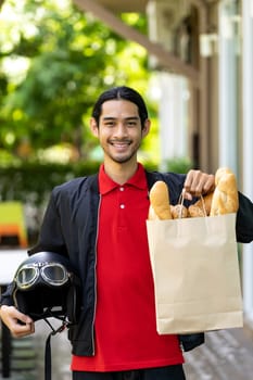 Portrait of attractive and smile asian deliverly bike man holding grocery bag from supermarket ready to deliver to online customer. Food deliverly and online order concept.