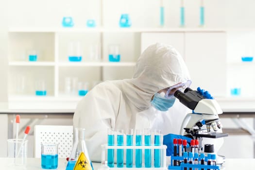 Young asian scientist doing some research and  looking through a microscope in a laboratory to study about coronavirus COVID-19 to develope vaccine for 2019-ncov world pandemic. Healthcare concept.