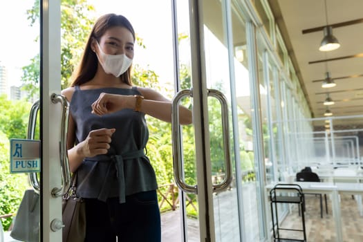 Portrait of asian attractive woman using elbow to push restaurant door open to reduce hand touching on public place to reduce chance to infection by coronavirus covid-19. New normal lifestyle concept