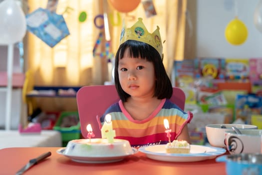 Asian girl kid with her birthday cake celebrate alone with family because city lockdown while COVID-19 Pandemic. Celbration and quarantine concept.