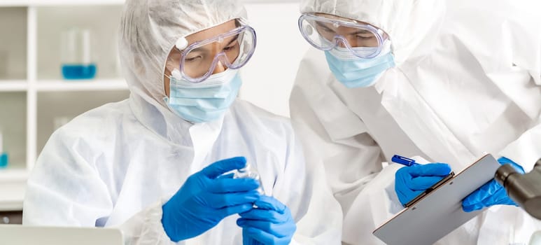 Panoramic Scientist examine vaccine testing of coronavirus covid-19 pandemic in science lab. Scientist wear PPE personal protective suits  and medical goggles. Medical Science and healthcare concept.