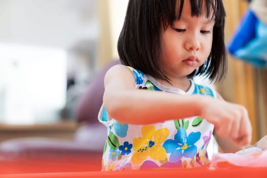 Asian girl child sewing in living room at home as home schooling while city lockdown because of covid-19 pandemic across the world. Home Scholling prepare for Preschool concept.