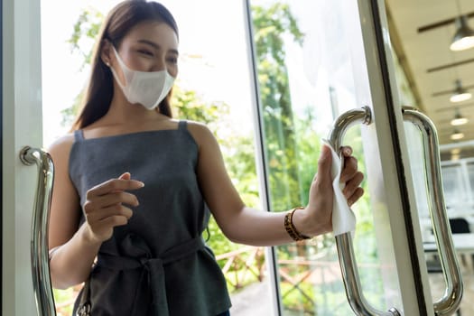 close up of asian woman hand with tissue paper to push restaurant door open reduce hand touching on public place to reduce chance to infection by coronavirus covid-19. New normal lifestyle concept