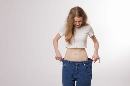 Shape slender, thin waist, attractive slim asian young woman, hand show shape her weight loss, wearing in big, large or oversize jeans, excess lose by diet and exercise. People body fit healthy.