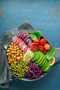Healthy vegan lunch bowl. Vegetable dishes with Avocado, chickpeas, tomato, red cabbage, green peas, red onion and egg