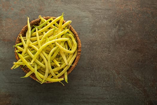Fresh picked yellow wax beans in to basket on dark background
