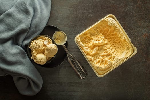 Fresh of vanilla ice cream scoops, scooped out of container in to bowl with a silver utensil