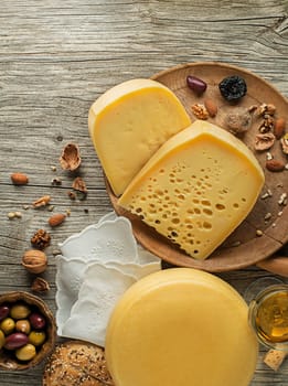 Assortment of cheeses, wine, nuts and fruits on a wooden table. Top view. Free space for text.