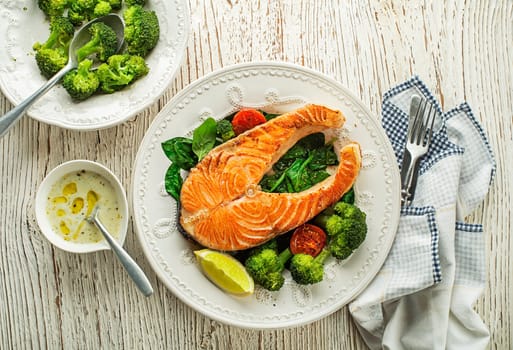 Fresh baked salmon steak with dressing sauce and vegetable on plate