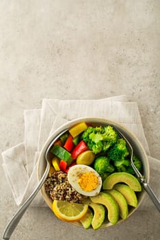 Healthy salad meal with quinoa, egg, avocado and mixed fresh vegetables on grey background top view. Food and health. Healthy meal concept