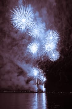 Premium entertainment magic star firework at e.g. New Years Eve or Independence Day party celebration. Nice lake surface reflections.