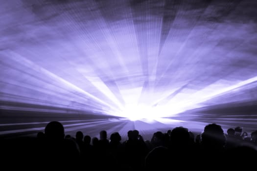 Luxury entertainment with audience silhouettes in nightclub event, festival or New Years Eve. Beams and rays shining colorful lights.