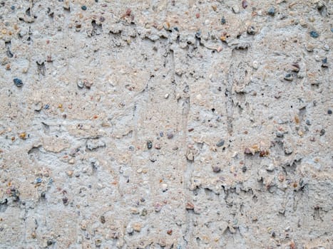 Format-filling view of a roughly plastered gray wall with coarse pebbles.