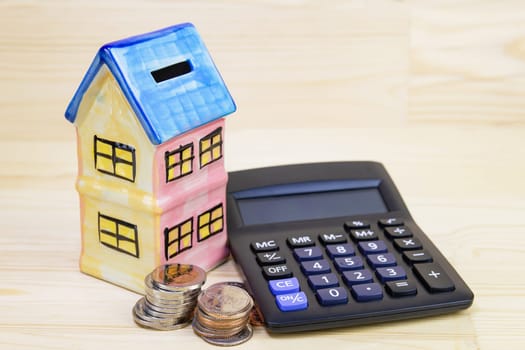 Model house with coin, calculator on wood table, concept .Collecting money Buying a house, residence, business, finance