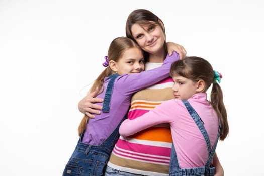 Children hug mom, mom looks happily in frame, isolated on white background