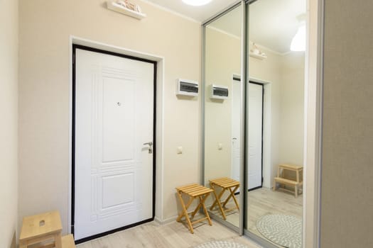 Entrance hall interior with metal front door and large sliding wardrobe with mirrors
