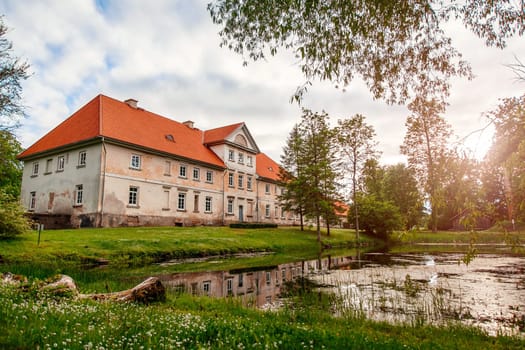 Municipal school in an old building with a pond in the yard. Historic Old Manor, Pope, Latvia