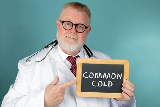 Doctor with eyeglasses holding chalkboard with Common Cold lettering on blue background