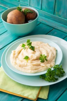 Mashed potatoes in bowl on blue teal wooden table, vertical image