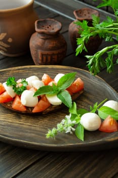 Bruschetta with red tomatoes, mozzarella cheese and basil on a old rustic dark table. Vertical image
