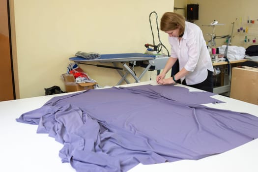 the cutter puts on the material details of clothing on patterns