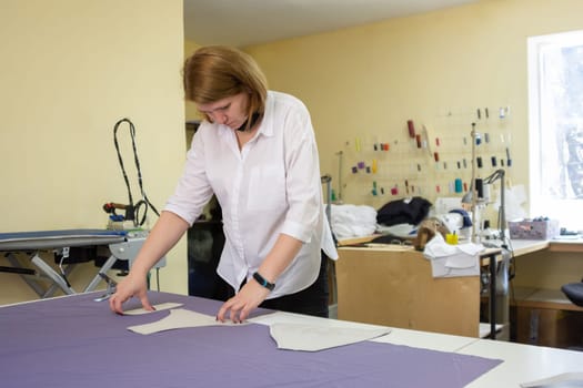 the cutter lays out the patterns on the matter on a large table in the workshop