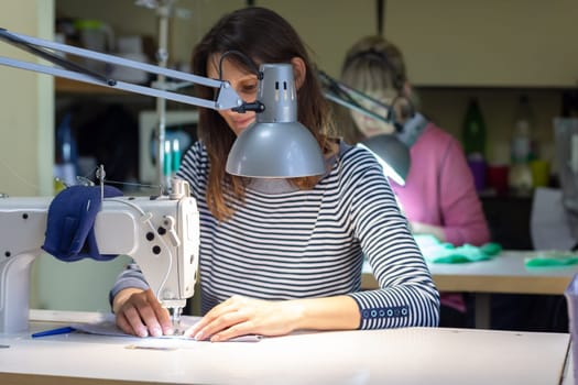 a seamstress scribbles on a sewing machine in a atelier at her workplace
