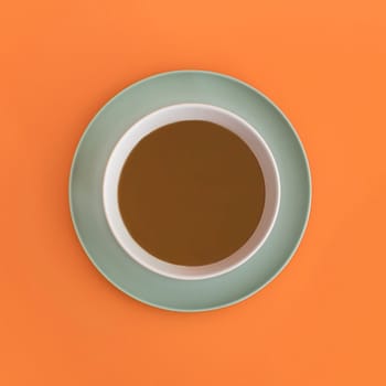 Chocolate bowl on a green light plate. Orange background. Top view. Copy space