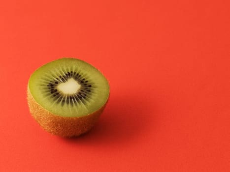 Close-up of a kiwi cut in half. Isolated on a red background. Copy space.
