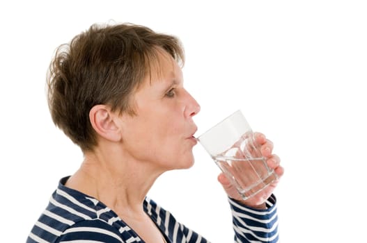 Profile view of the head and shoulders of an elderly woman in a striped shirt holding a glass of water to her mouth against white background.