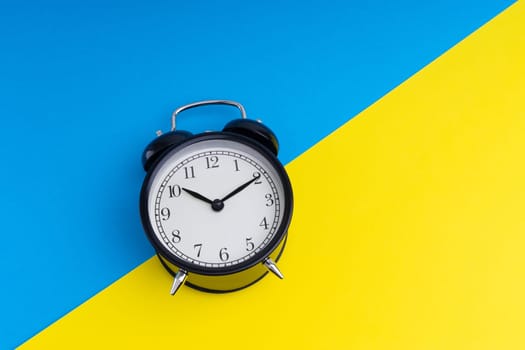Alarm clock on a blue and yellow background. Business Concept