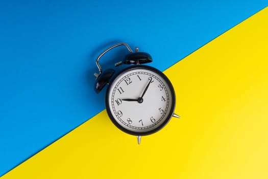 Alarm clock on a blue and yellow background. Business Concept