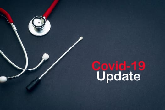 COVID-19 UPDATE text with stethoscope and medical swabs on black background. Covid -19 or Coronavirus Concept
