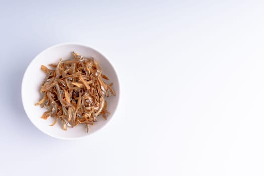 Fried anchovies in bowl close up with selective focus and crop fragment