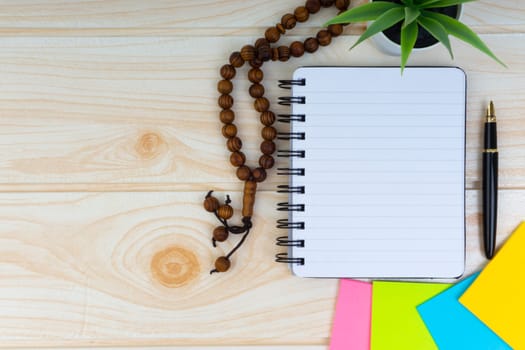 Flat lay view of workspace with Pen, spectacles, decoration flower, rosary and book.Copy Space, business and education concept.