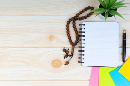 Flat lay view of workspace with Pen, spectacles, decoration flower, rosary and book.Copy Space, business and education concept.