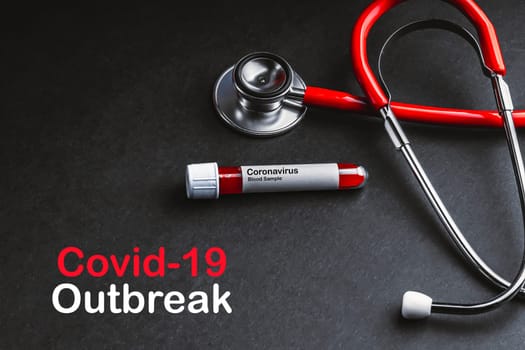 COVID-19 OUTBREAK  text with stethoscope and blood sample vacuum tube on black background. Covid or Coronavirus Concept
