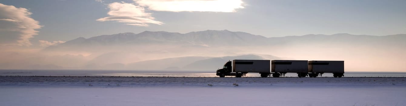 Fresh snow covers the ground trucks pass late in the day on this lonely highway