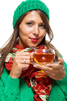 Attractive woman with green wool hat in winter drinks a cup of tea isolated against a white background
