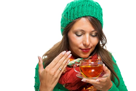 Attractive woman with green wool hat in winter drinks a cup of tea isolated against a white background