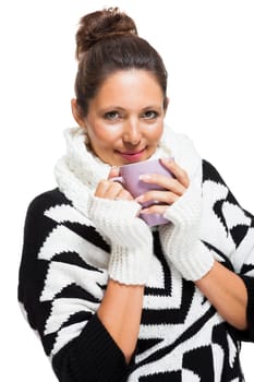 young attractive woman with black and white wool sweater drinking a cup of coffee or tea and warms your hands on the cup isolated on white background