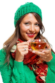 Attractive woman with green wool hat in winter drinks a cup of tea isolated against a white background