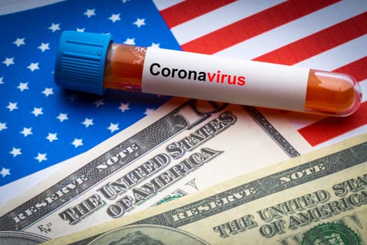 CORONAVIRUS COVID-19 text, US Dollar and blood sample vacuum tube on America flags background. Covid-19 or Coronavirus Concept