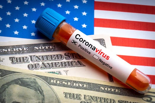 CORONAVIRUS COVID-19 text, US Dollar and blood sample vacuum tube on America flags background. Covid-19 or Coronavirus Concept