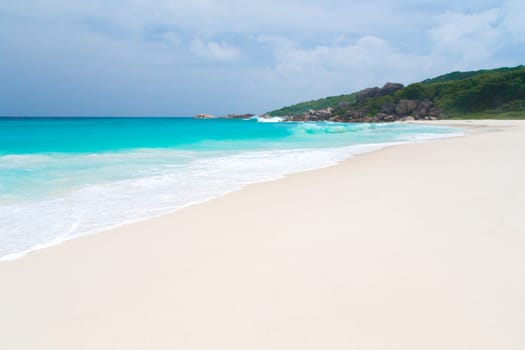 The beach on the Seychelles with white sand turquoise water and blue sky
