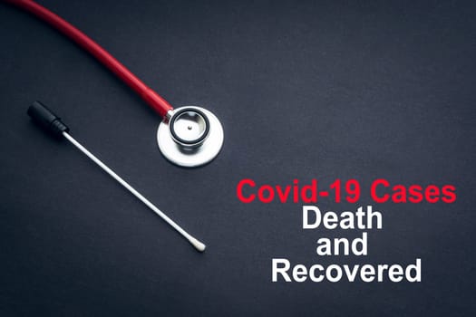 COVID-19 or CORONAVIRUS DEATH AND RECOVERED text with stethoscope and medical swab on black background. Covid-19 or Coronavirus concept.
