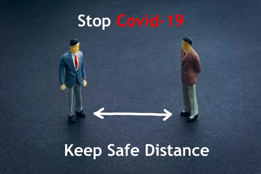 STOP COVID-19 KEEP SAFE DISTANCE text with miniature people on dark background. Covid-19 or Coronavirus concept