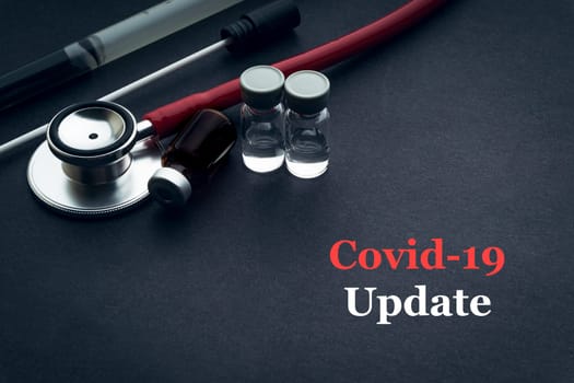 COVID-19 or CORONAVIRUS UPDATE text with stethoscope, medical swab and vial on black background. Covid-19 or Coronavirus concept.